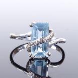 A 9ct white gold blue topaz and diamond ring, wrap-over diamond band, topaz length 11.9mm, size S,