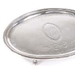 A George III silver oval teapot stand, bright-cut engraved decoration and central bow cartouche,