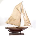 A 19th century wooden-hulled model pond yacht with masts and rigging, hull length 1.1m, on wooden