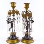 A pair of Regency bronze and ormolu cherub candlesticks, with painted enamel cherub decorated