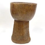 A floor standing Tribal mortar bowl, carved from a single piece of wood, height 73cm, diameter 47cm