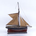 A handmade carved and painted wood pond yacht, with string rigging and canvas sails, hull length