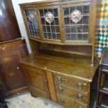 An Arts and Crafts oak 2-section dresser, the bow-front top with leadlight glazed panels and