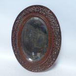 A carved and pierced hardwood framed oval mirror, height 47cm