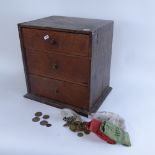An engineer's table-top oak chest of drawers, containing various British pre-decimal coins, chest