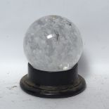 A polished translucent clear glass crystal ball on ebonised stand, ball diameter 12cm