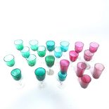 A collection of various cranberry and green glass drinking glasses and beakers