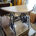 A mahogany demilune console table on a Singer sewing machine treadle base, W100cm, D47cm, H74cm