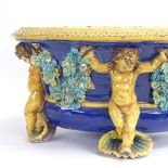 A large 19th century glaze Majolica pottery jardiniere, with supporting cherubs and grapevine swags,