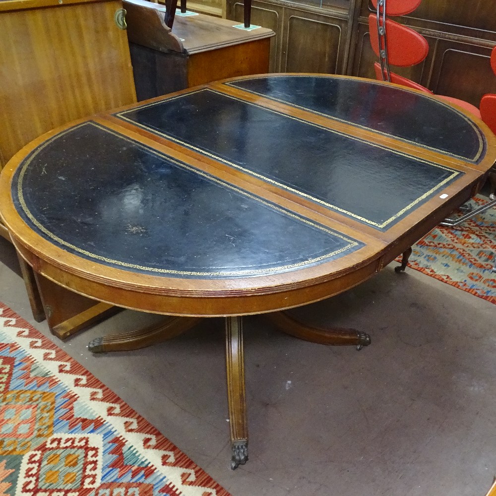 A reproduction mahogany bow-end pull-out dining/boardroom table, having tooled black leather