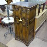 A Titchmarsh & Goodwin Ipswich oak design music cabinet, with 4 fielded panelled cupboards doors,