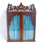 A Black Forest style hanging display cabinet, with pierced oak leaf frieze and glazed doors,