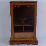 A Victorian oak smoker's display cabinet, with brass swing handles, glazed door and fitted interior,