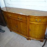 A reproduction crossbanded yew wood sideboard, bow-front form with frieze drawers and cupboards