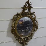 An ornate gilt-gesso framed convex wall mirror with twin candle brackets, overall height 90cm