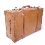 A large leather-bound Vintage travelling suitcase, with fastening straps and carrying handles,