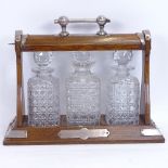 A Victorian oak tantalus with electroplate mounts, containing 3 square cut-glass decanters, all