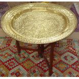 A large Eastern embossed brass sweet meat dish top, on folding base, W90cm