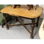 A 1920s oak round-cornered pop-up extending dining table on cross stretchers, with turned baluster