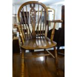 An early 20th century elm-seated wheel-back elbow chair