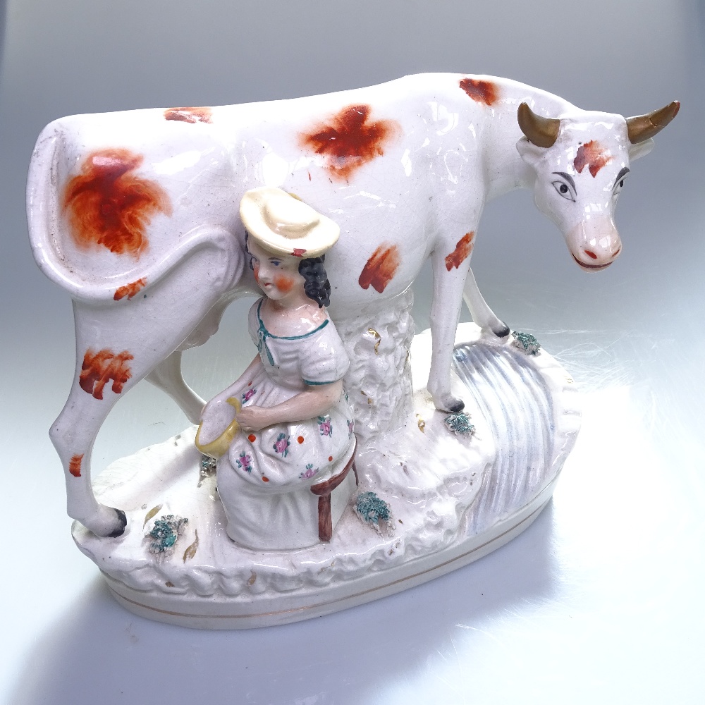 An early Staffordshire figure of a cow with milkmaid, on plinth, height 16cm