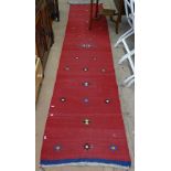 A red ground flat weave Kilim runner, 322cm x 68cm