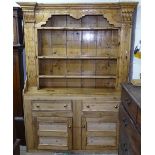 An Antique style polished pine 2-section dresser, having a boarded open plate rack, base fitted with