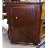 A George III oak hanging corner cupboard, with shaped shelved interior and single panel door, W74cm