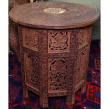 An Eastern carved hardwood circular table, with inset bone decoration, on panelled folding base