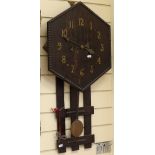 An Arts and Crafts oak hexagonal wall clock, beaded edge with picket drop, with key and pendulum,