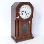 An Art Nouveau oak-cased 8-day mantel clock, column supports with glass pendulum viewing aperture,