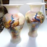 A pair of Royal Worcester porcelain vases, with painted designs of peacocks in branches, height 31cm