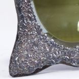 A large Elizabeth II silver-fronted strut dressing table mirror, relief embossed foliate decoration,