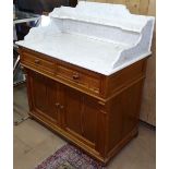 A pitch pine washstand with a shaped raise marble top, with fitted drawers and cupboards, on bun