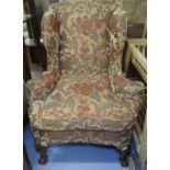 A Victorian upholstered wing fireside armchair, raised on shell-carved cabriole legs, with claw