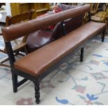 An early 20th century studded rexine upholstered and ebonised station waiting room bench, on