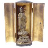 A Japanese gilt black lacquer travelling Zushi shrine, containing gilt standing deity on lotus base,