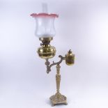 A 19th century brass oil lamp, relief embossed cherub base with frosted frilled glass shade and