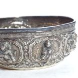 A small Burmese unmarked white metal Thabeik bowl, high relief figural and lotus decoration with