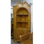 A large polished pine open corner display cabinet, with swan-neck pediment and starburst recessed