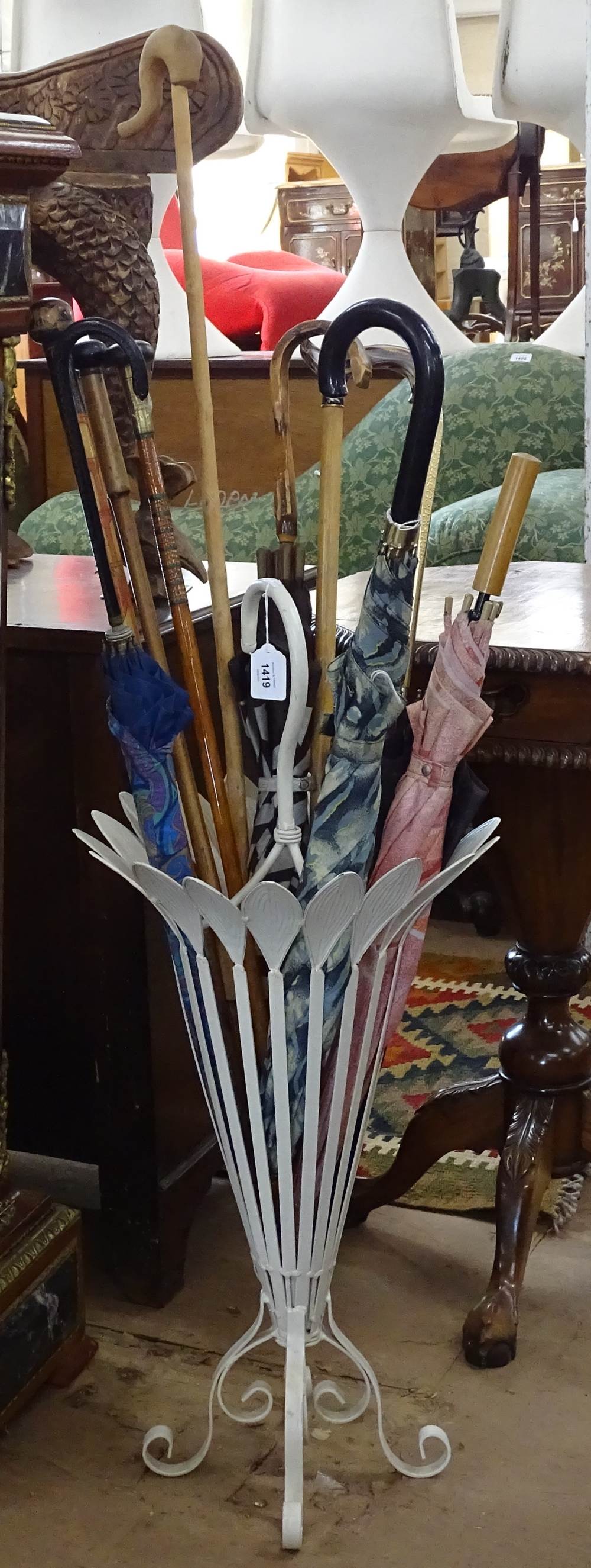 A cream painted metal stick stand, and a quantity of umbrellas, parasols and sticks