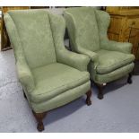 A pair of Edwardian upholstered wingback fireside armchairs, on carved cabriole legs, with hoof feet