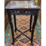 A Chinese design padauk wood lamp table, with a carved and pierced frame, cross stretchers raised on