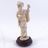 A late 19th century/early 20th century Japanese carved ivory okimono, depicting lady playing