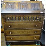 A 1930s oak bureau, with linenfold panelled front and 4 long drawers under, on bun feet, W77cm