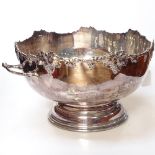 A large silver plate on copper 2-handled punch bowl, with cast grape and vine-shaped edge on