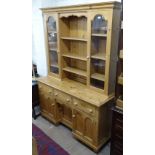 A polished pine 2-section kitchen dresser, with glazed cupboards above a kneehole base with fitted