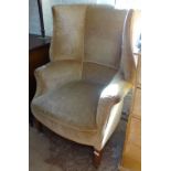 An Edwardian wing upholstered armchair, with tapered mahogany legs