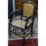 A Chinese designed black lacquered and gilded armchair, with cane panels