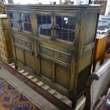 An oak side cabinet with leadlight glazed and carved panelled cupboard doors, W130cm